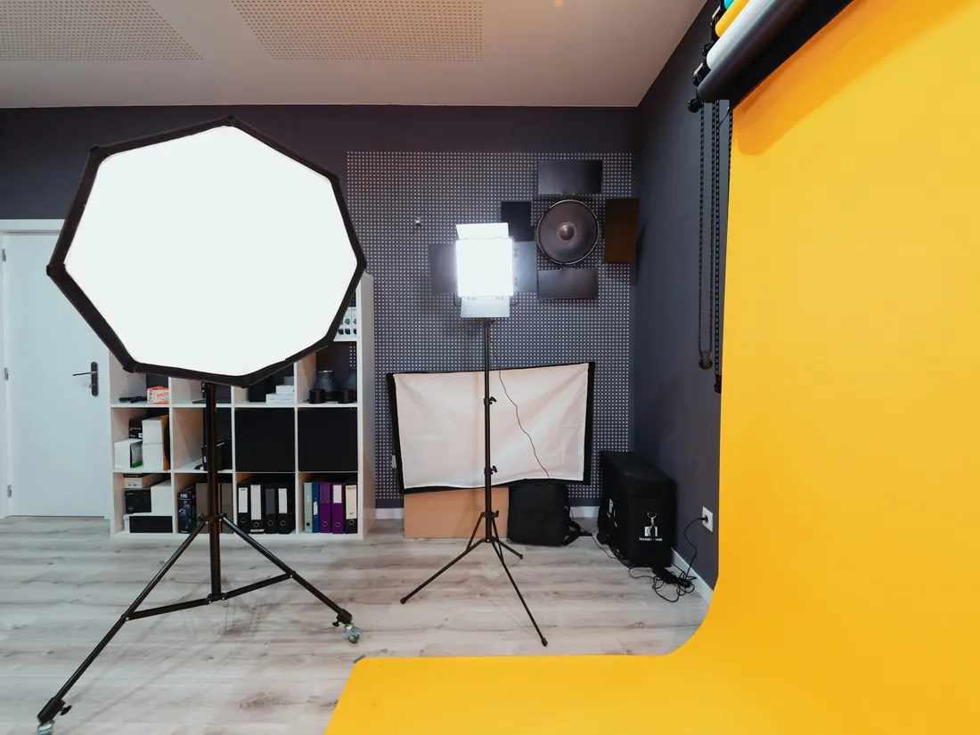 Plató fotográfico con un octabox montado sobre pie, un panel de luz continua y un rollo de fondo de papel amarillo desplegado hasta el suelo